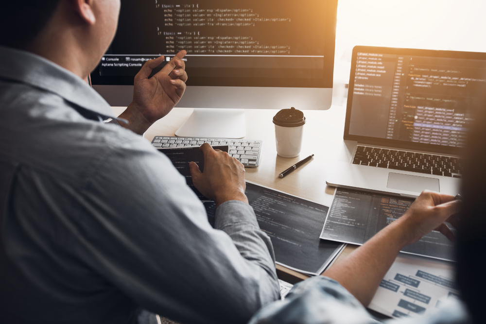 兩名軟件開發(fā)人員正在使用計算機與辦公桌上的合作伙伴一起工作